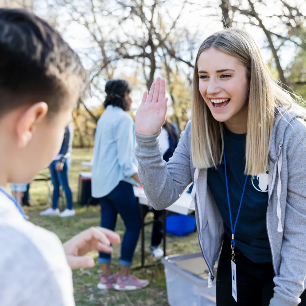 Image of a woman welcoming a young boy by a high five